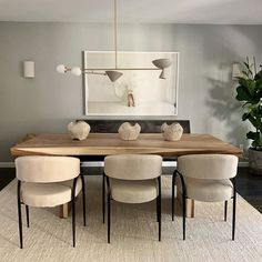 a dining room table with four chairs and a large painting on the wall behind it