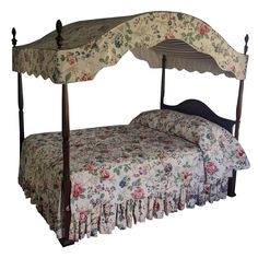 a canopy bed with floral bedspread and matching pillows on the bottom, along with two night stands