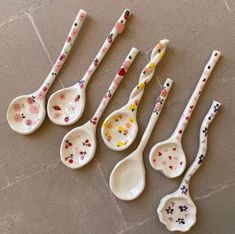 six spoons with different designs are lined up on the floor