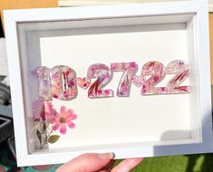 a person holding up a frame with flowers in it that reads $ 2, 722