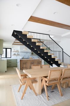 a dining room table and chairs under a stair case