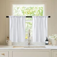 a kitchen window with white curtains in front of it