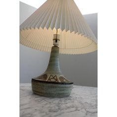 a lamp sitting on top of a table next to a white vase with a bird on it