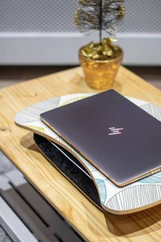 an open laptop computer sitting on top of a wooden table next to a potted plant