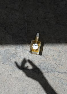 the shadow of a person's hand casting a shadow next to a bottle of cologne