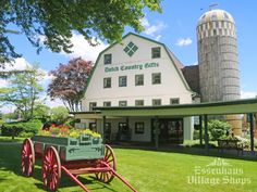 an old fashioned wagon with flowers in front of a large white building on the grass