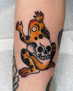 a tattoo with a frog on it's leg and a skull in the middle