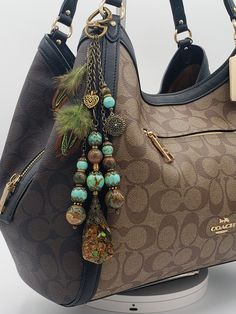 a brown coach purse with blue and green beads hanging from it's front pocket