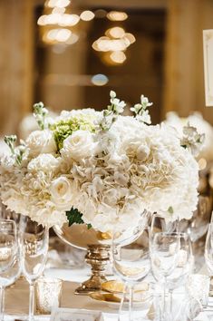 an image of a table setting with white flowers and wine glasses on the table in front of it