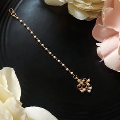 a close up of a necklace on a black plate with flowers in the back ground