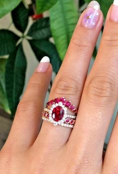 a woman's hand with pink and white manicured nails holding two different colored rings