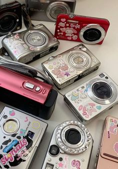 there are many different types of cameras on the table together, including one with hello kitty stickers