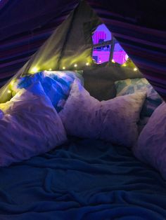 a bed with pillows and lights in a tent at night, under the covers is a lit up teepee