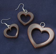 three wooden heart shaped earrings on a blue background with silver earwires and hooks