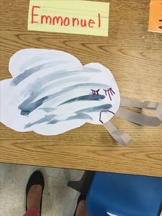 a child's feet on a desk with a paper cut out of a cloud