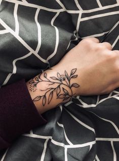 a woman's arm with a flower tattoo on it, resting on a bed