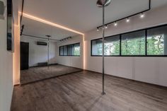 an empty room with wooden floors and large mirrors on the wall, along with floor to ceiling windows