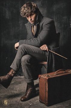 a young man sitting on top of a chair next to a suit case and tie