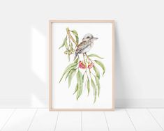 a bird sitting on top of a tree branch next to a wall mounted art print