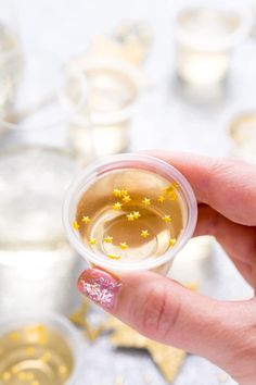 a hand holding a small cup filled with liquid and gold stars on the rims