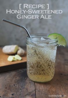 a glass filled with liquid next to a wooden cutting board and lime slice on the table