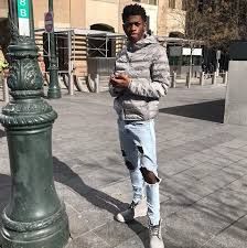 a man standing next to a green pole on the sidewalk looking at his cell phone