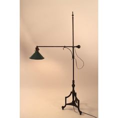 an old fashioned floor lamp with a green shade on the base and a black arm