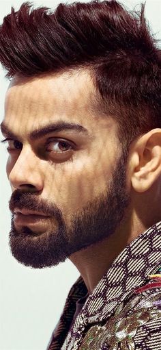 a close up of a person with a beard wearing a shirt and looking off to the side