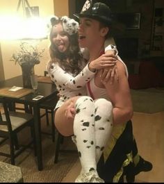 a man and woman dressed up as dalmatian dogs sitting on top of each other