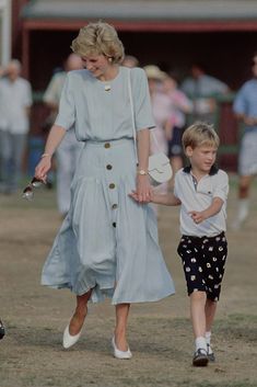 the princess and her son are walking through an open field with people in the background