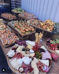 many different types of food are displayed on wooden tables with pineapples and other fruits