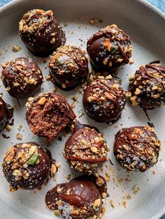 chocolate covered desserts are on a plate with nuts and other toppings around them