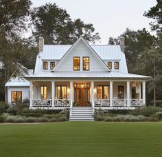 a white house with porches and windows in the front yard, surrounded by trees