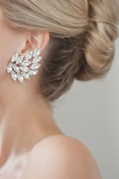 a close up of a woman's ear wearing large earrings with crystal stones on them