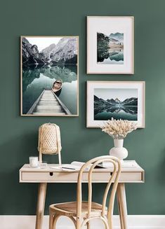 a desk with a chair and pictures on the wall above it, along with a vase filled with flowers