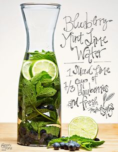 a pitcher filled with water next to sliced limes and blueberries