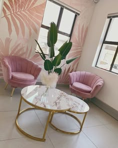 a living room with pink chairs and a marble coffee table in front of two large windows