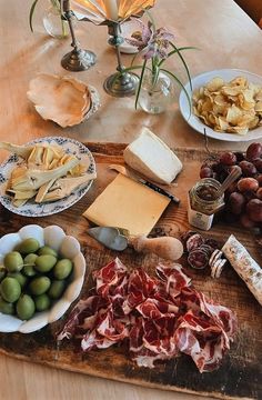 a wooden table topped with different types of cheese and meats on top of it