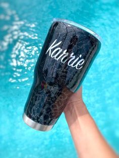 a hand holding up a black and silver can with the word karmie written on it