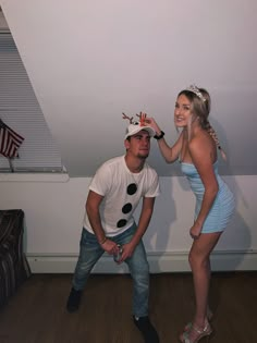 a man and woman standing next to each other in front of a wall with an american flag on it