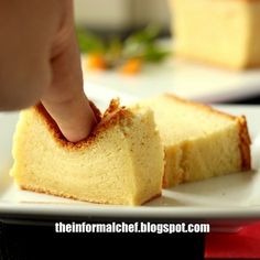 a piece of cake on a white plate with a hand reaching for the top slice