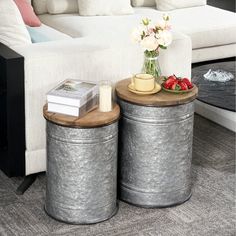 two metal canisters sitting on top of each other in front of a white couch