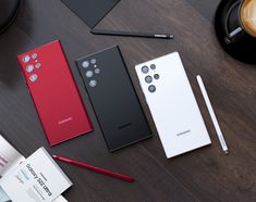 three different models of the same cell phone on a table next to a cup of coffee