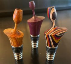 three different colored vases sitting next to each other on a black counter top in front of a window