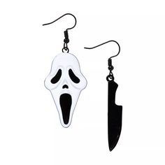 a pair of black and white earrings with a ghost face hanging from it's hooks