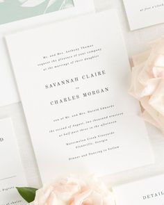 the wedding stationery is laid out on top of each other, with pink flowers