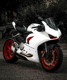 a white and red motorcycle parked on top of a brick road