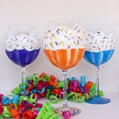 three wine glasses decorated with colorful confetti and ribbons