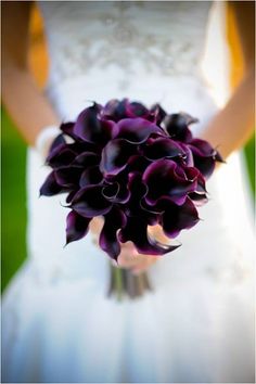 a bride holding a bouquet of purple flowers