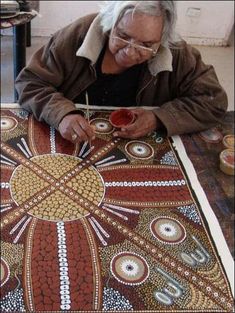 an older man is painting on a large piece of cloth